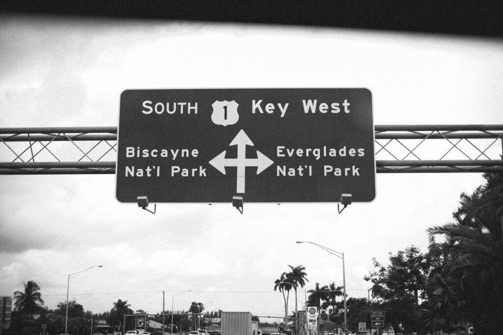 a black and white photo of the Key West road sign from South Miami